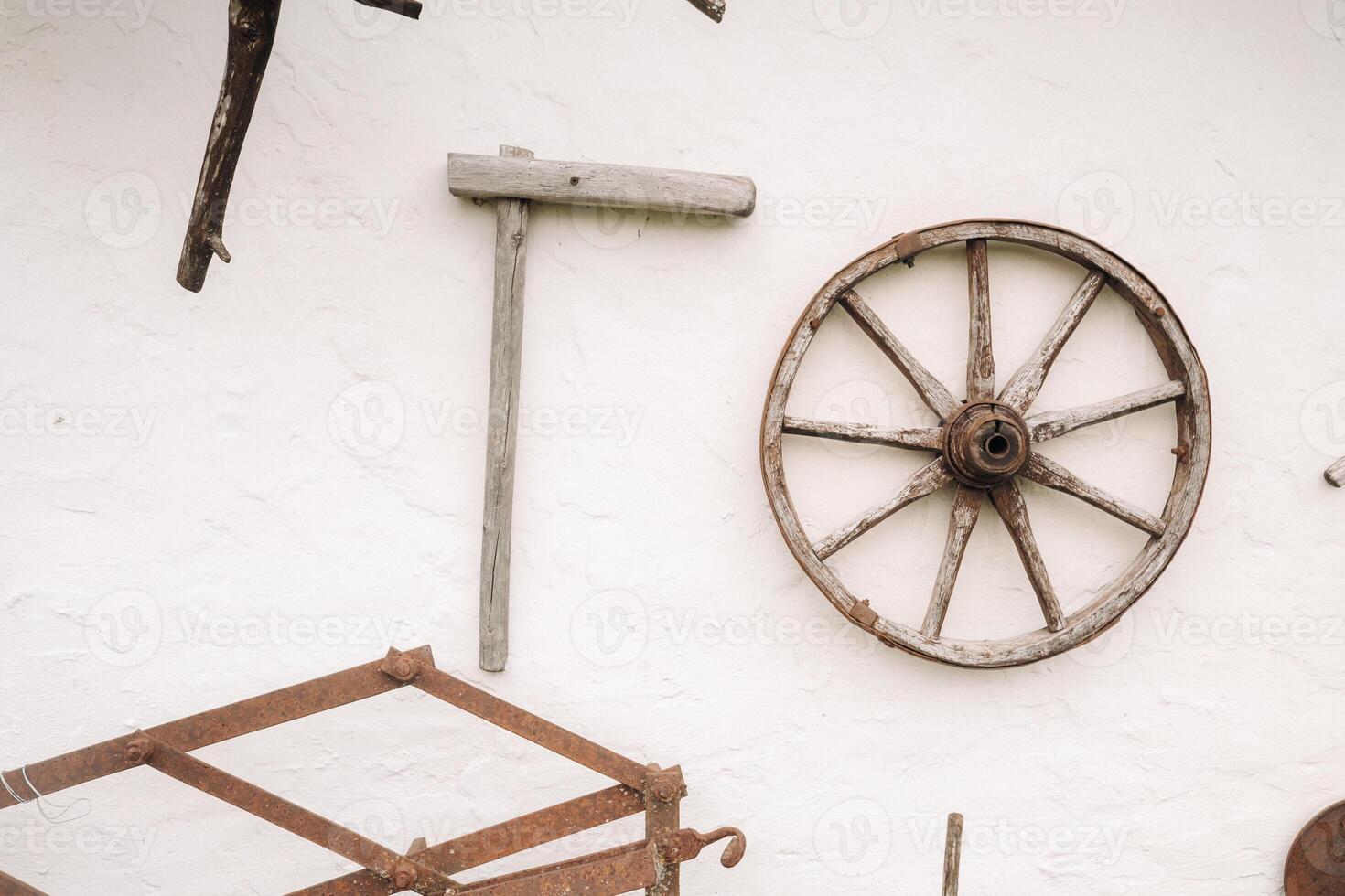 An old wooden wall of a house in the village and ancient cart wheels, tools, etc photo