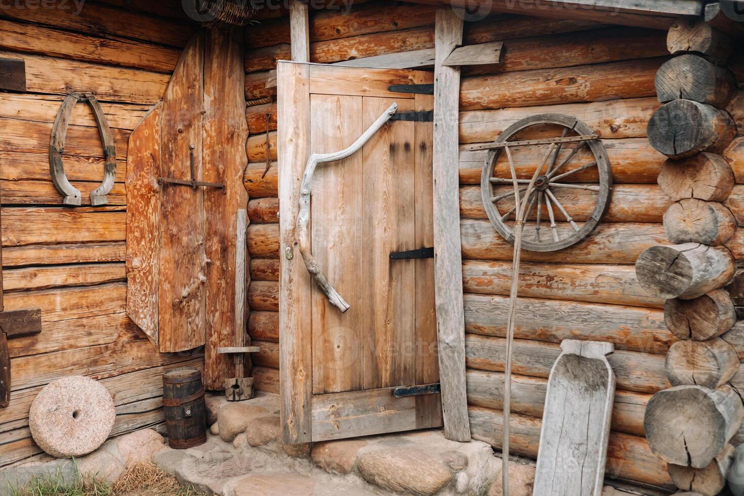 An old wooden wall of a house in the village and ancient cart wheels, tools, etc photo