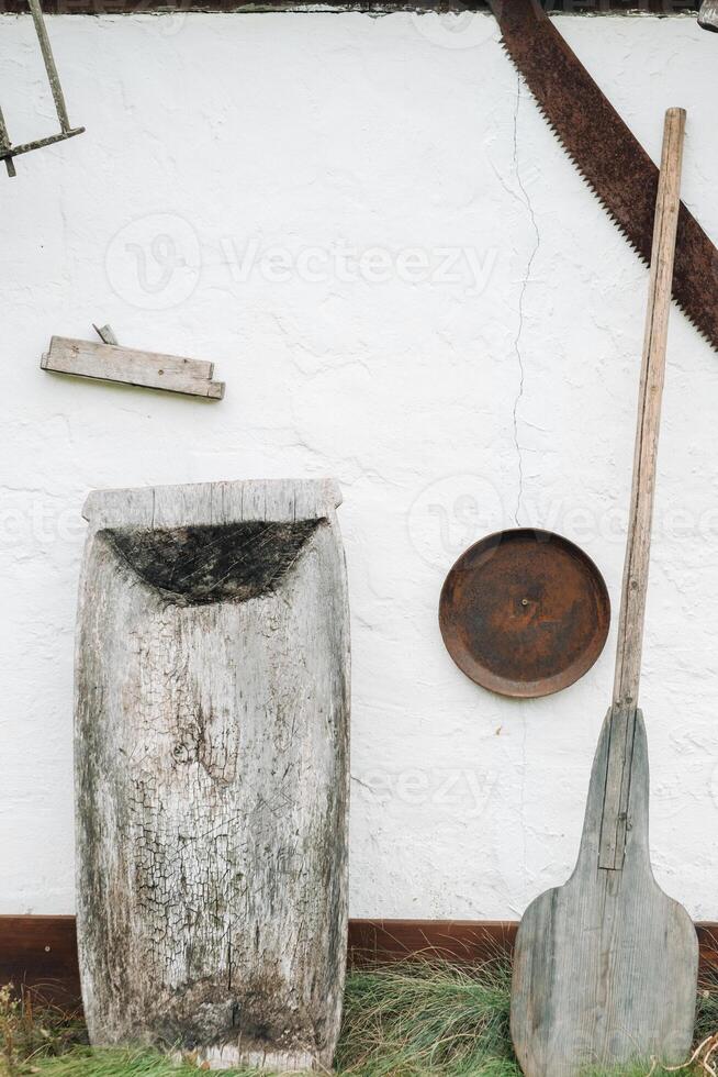 An old wooden wall of a house in the village and tools near the wall photo