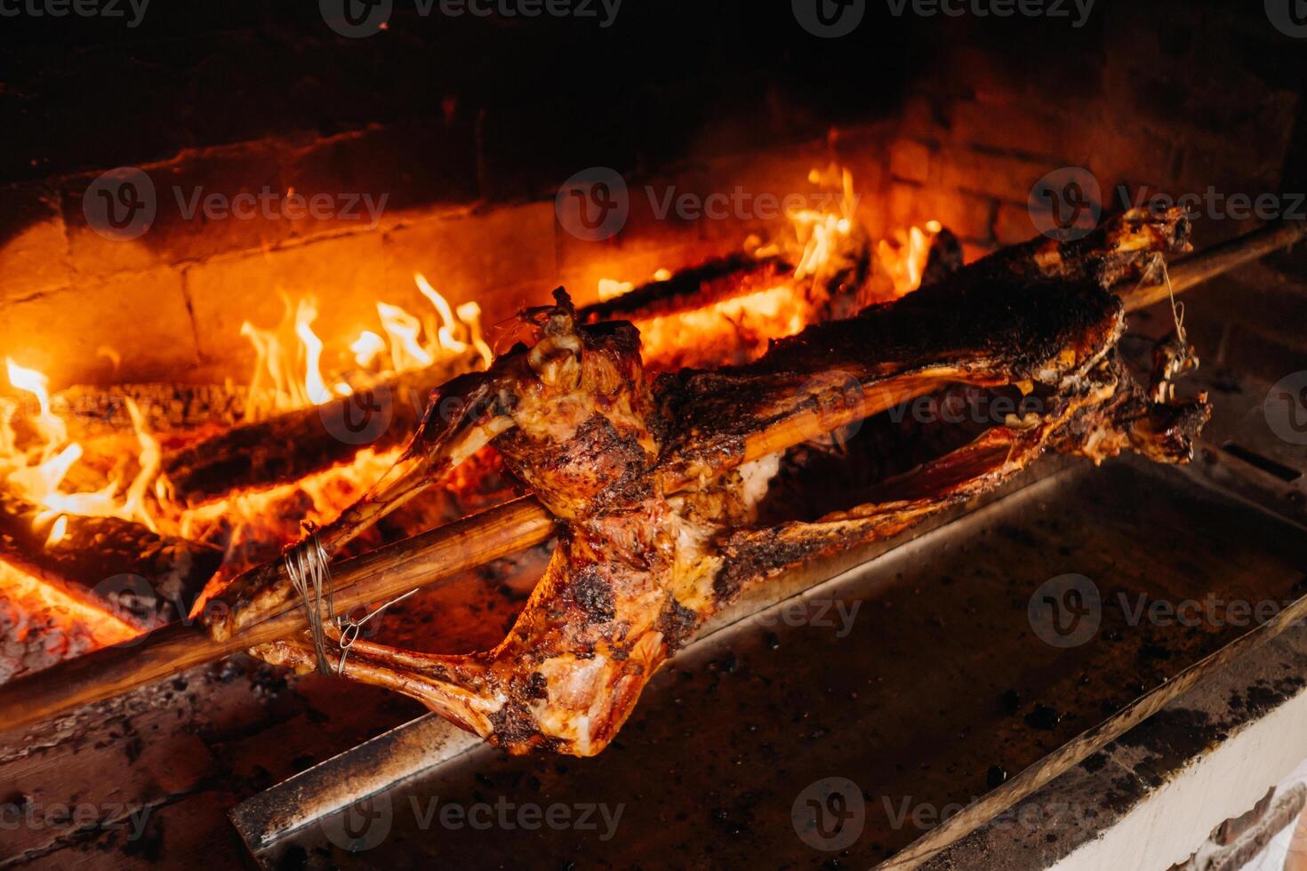 The lamb is cooked entirely on a spit on the fire. Cooking photo