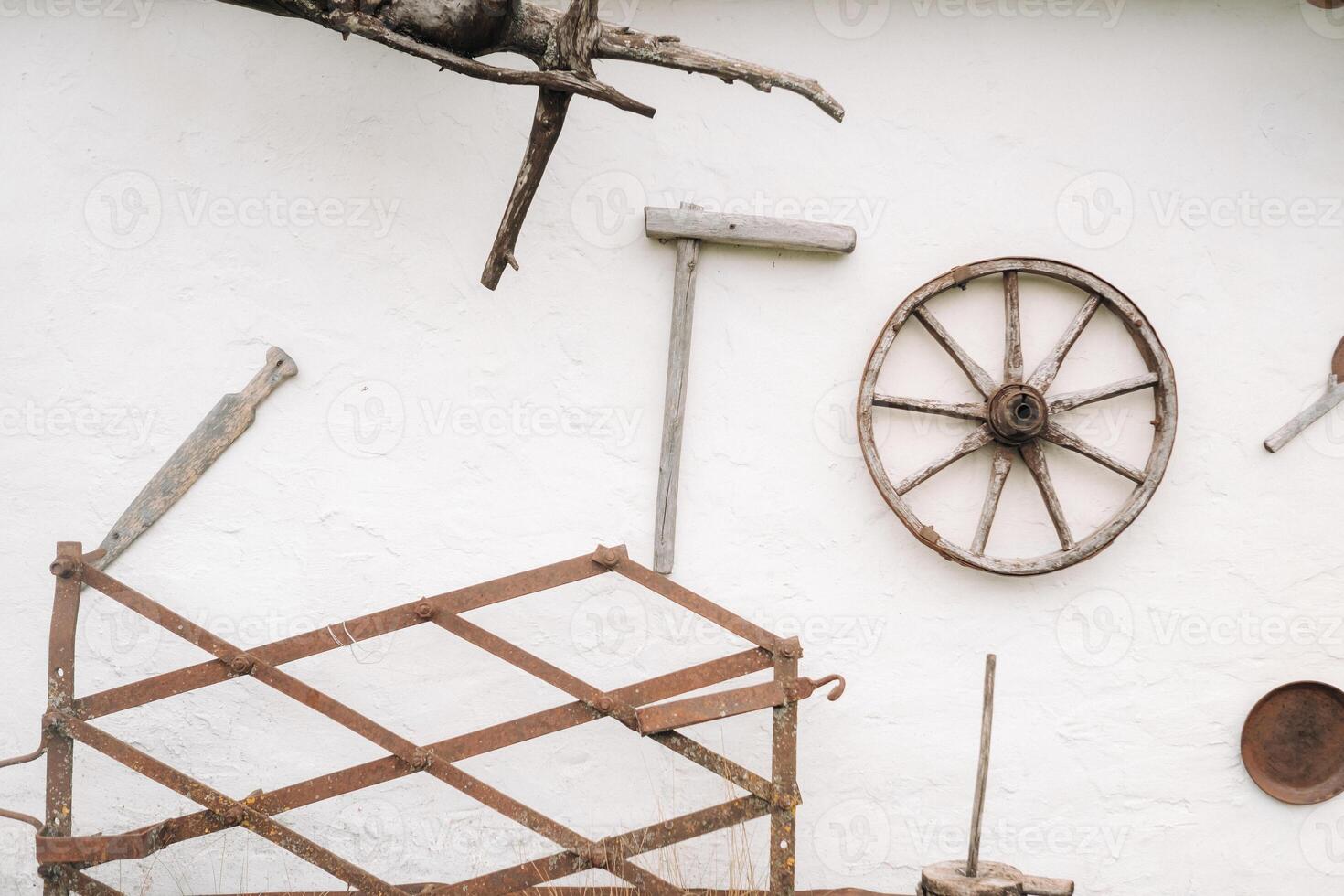 An old wooden wall of a house in the village and ancient cart wheels, tools, etc photo