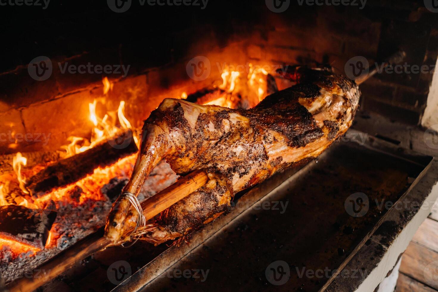 The lamb is cooked entirely on a spit on the fire. Cooking photo
