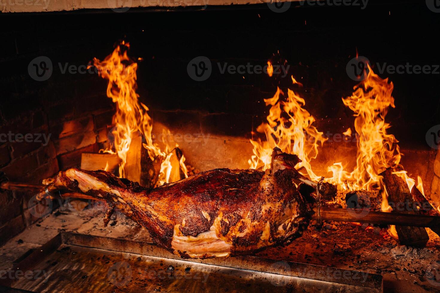 The lamb is cooked entirely on a spit on the fire. Cooking photo