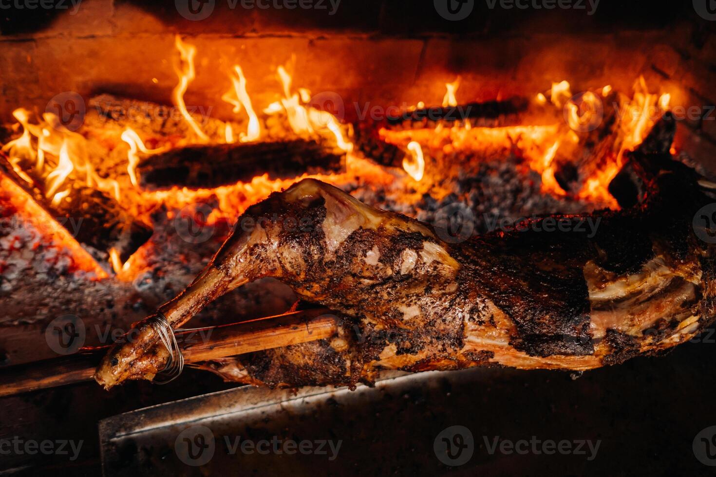 The lamb is cooked entirely on a spit on the fire. Cooking photo