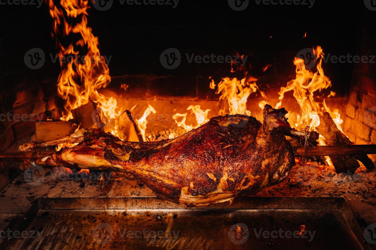 The lamb is cooked entirely on a spit on the fire. Cooking photo
