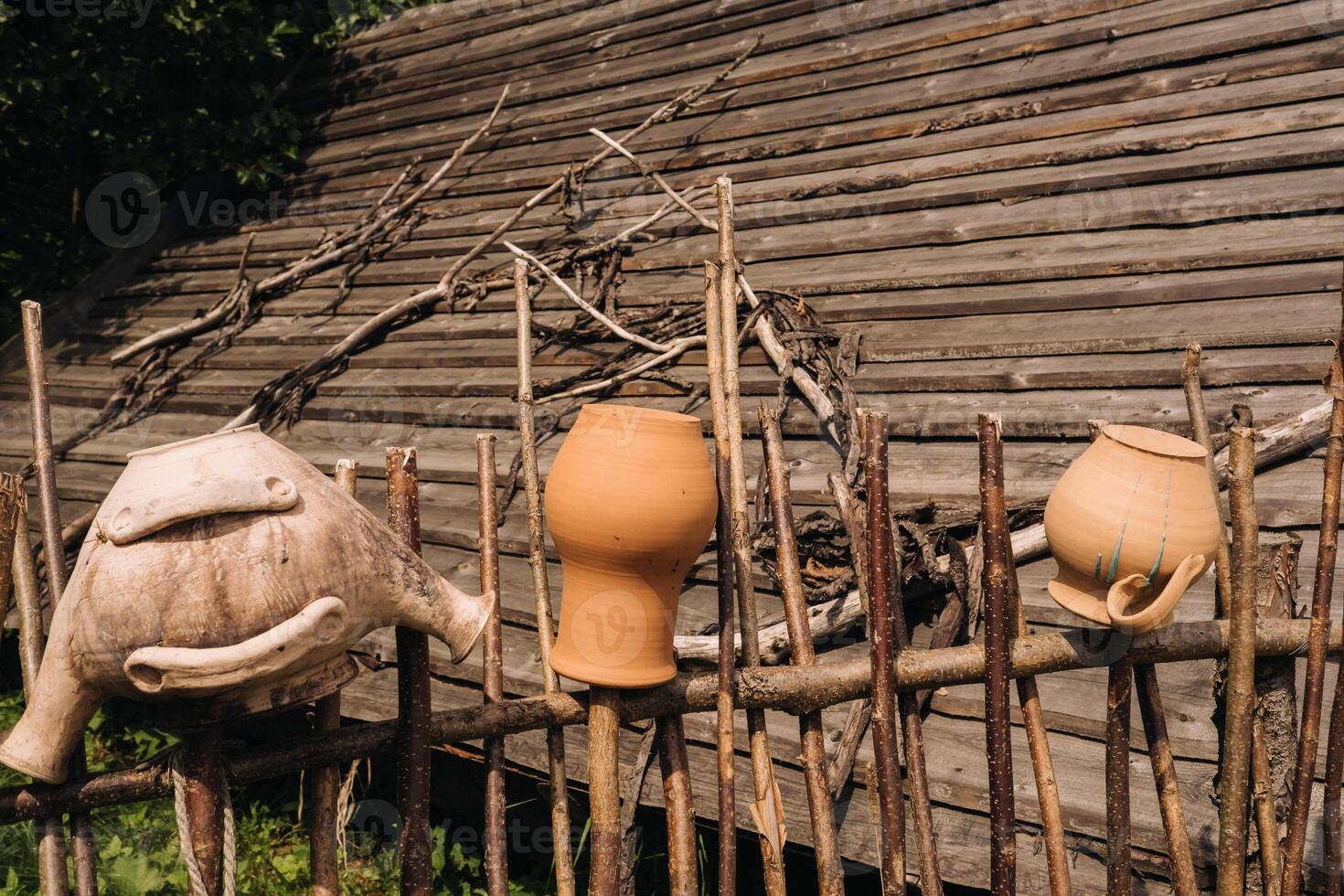 old clay pots just hang on a wicker fence. Ukrainian ethnic dishes, traditional culture of Ukraine photo