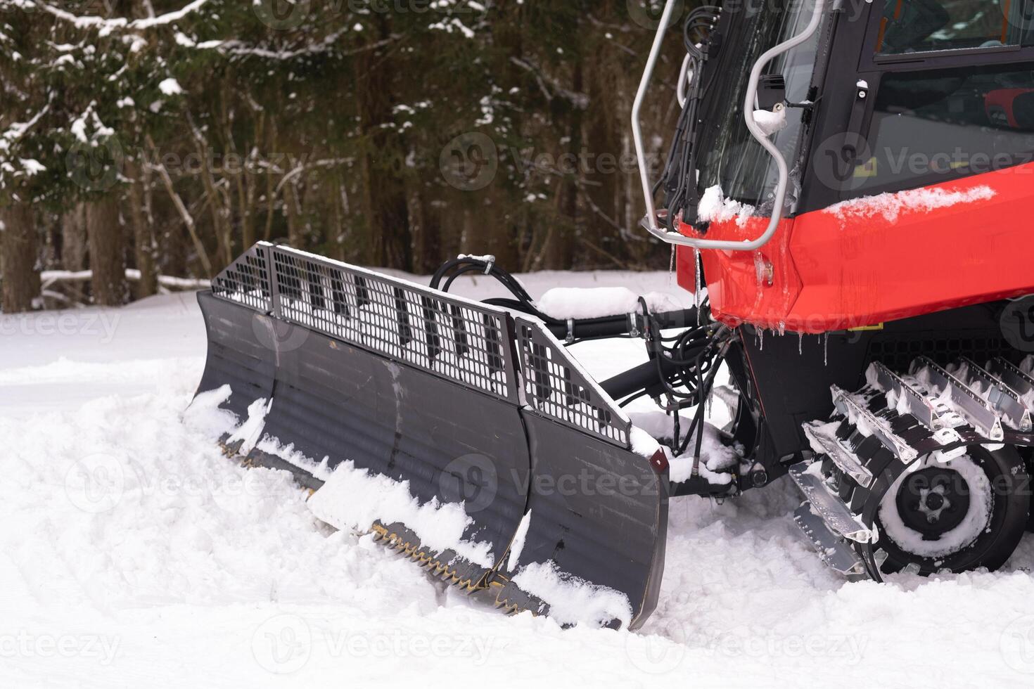 The bucket of a snowplow on tracks, standing in the forest in winter photo