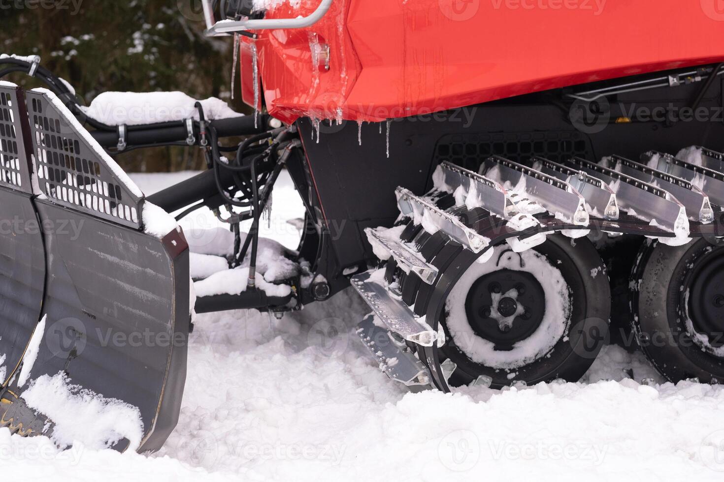 A snowplow on red tracks standing in winter in the forest near the barn photo