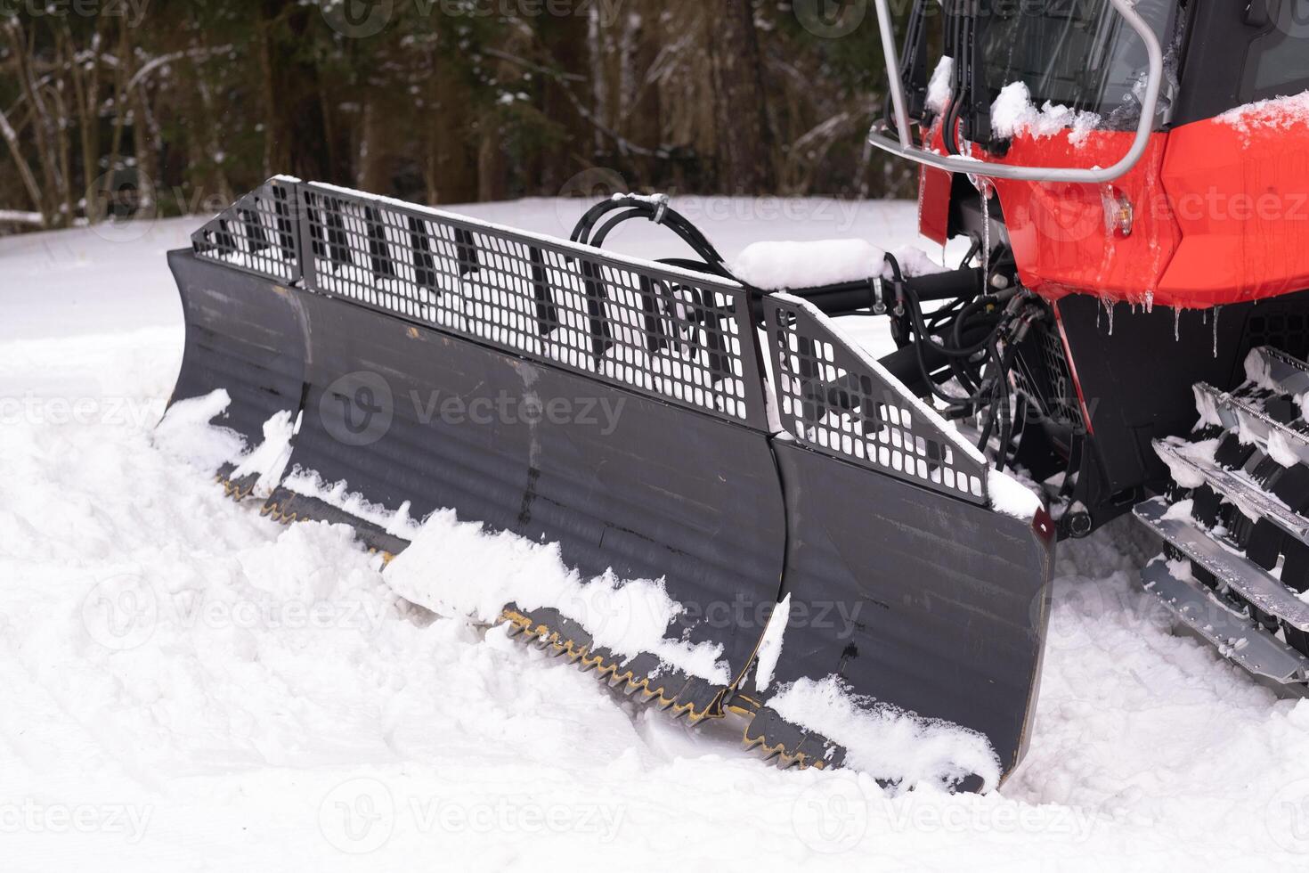 The bucket of a snowplow on tracks, standing in the forest in winter photo