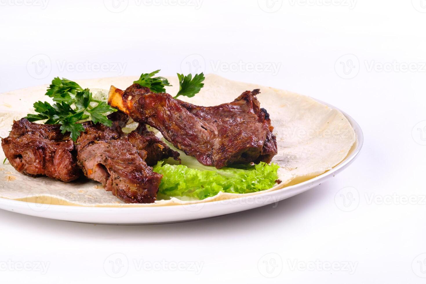 Meat kebab on ribs on lavash with onions and cabbage on a white plate, on an isolated white background photo