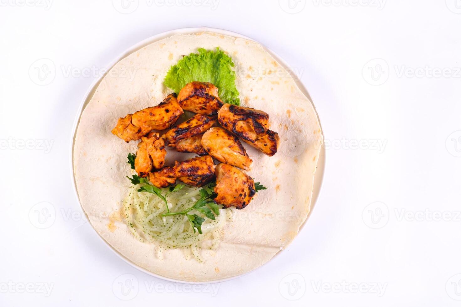 Chicken meat on pita bread with vegetables on a white plate on a white isolated background photo