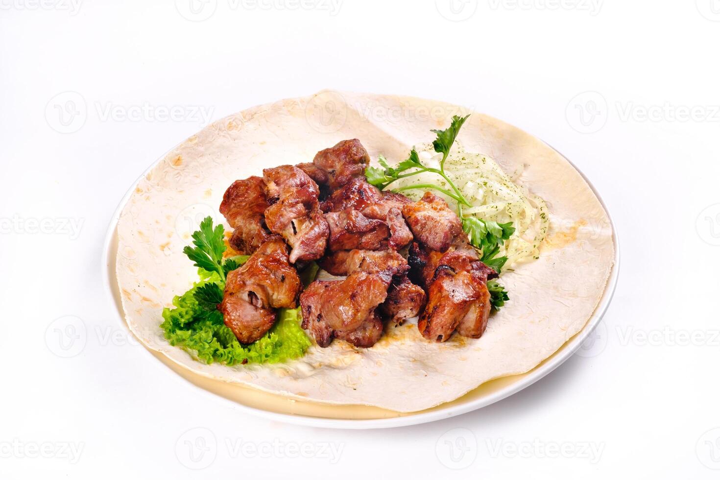 Pork shish kebab on lavash lies in a white plate on a white isolated background photo