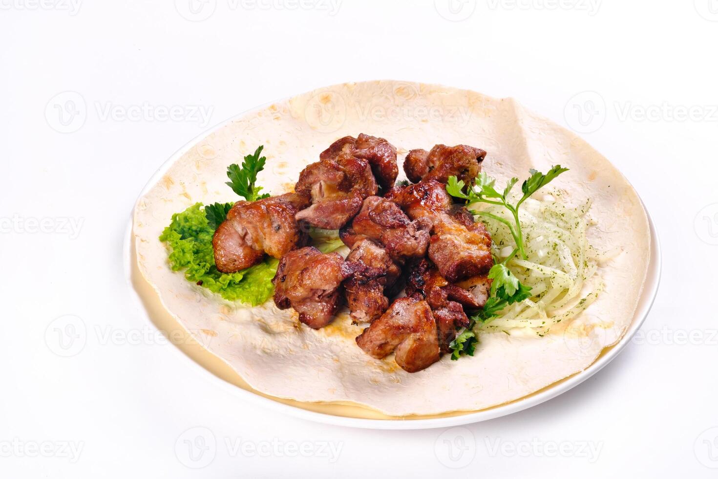 Pork shish kebab on lavash lies in a white plate on a white isolated background photo