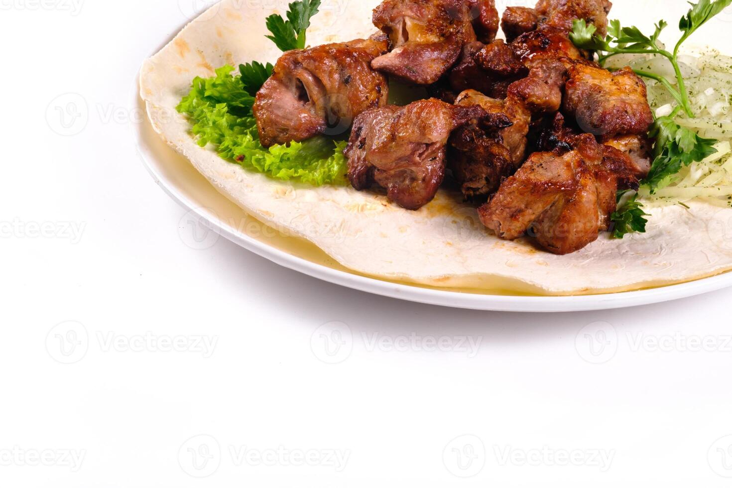 Pork shish kebab on lavash lies in a white plate on a white isolated background photo