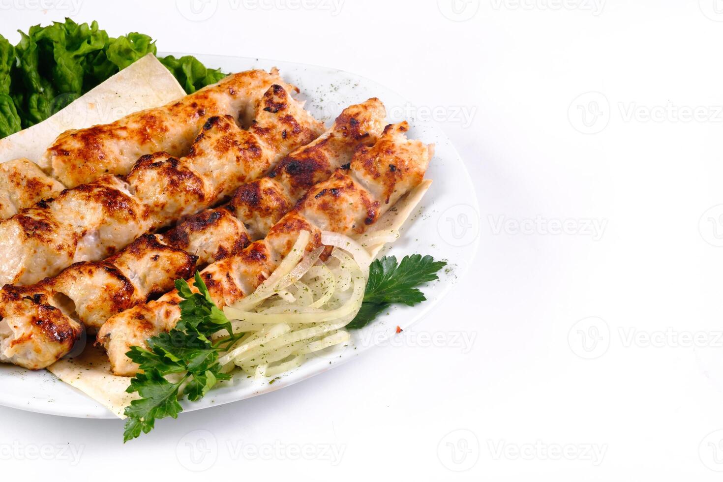 Homemade kebab on skewers with pita bread, onions, cabbage, vegetables, on a white plate on an isolated white background photo