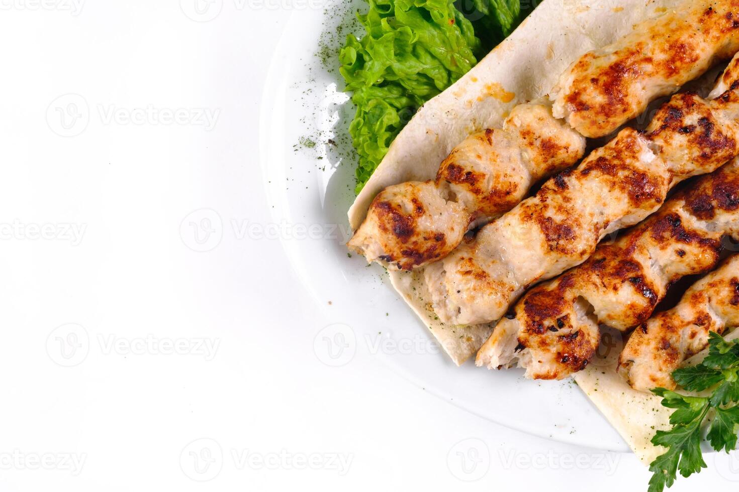 Homemade kebab on skewers with pita bread, onions, cabbage, vegetables, on a white plate on an isolated white background photo