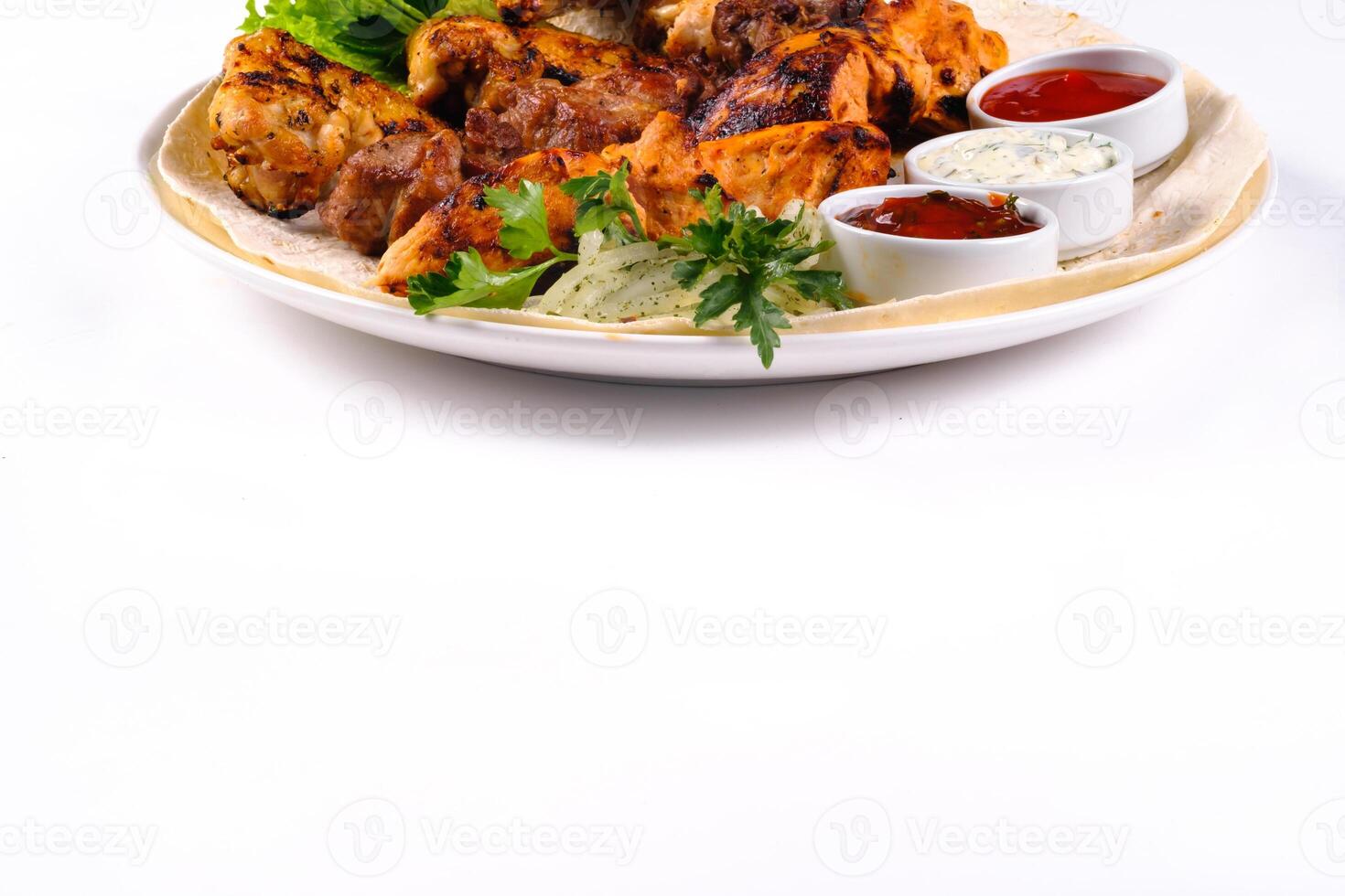 assorted meat on pita bread with vegetables and sauces on a white plate on a white isolated background photo