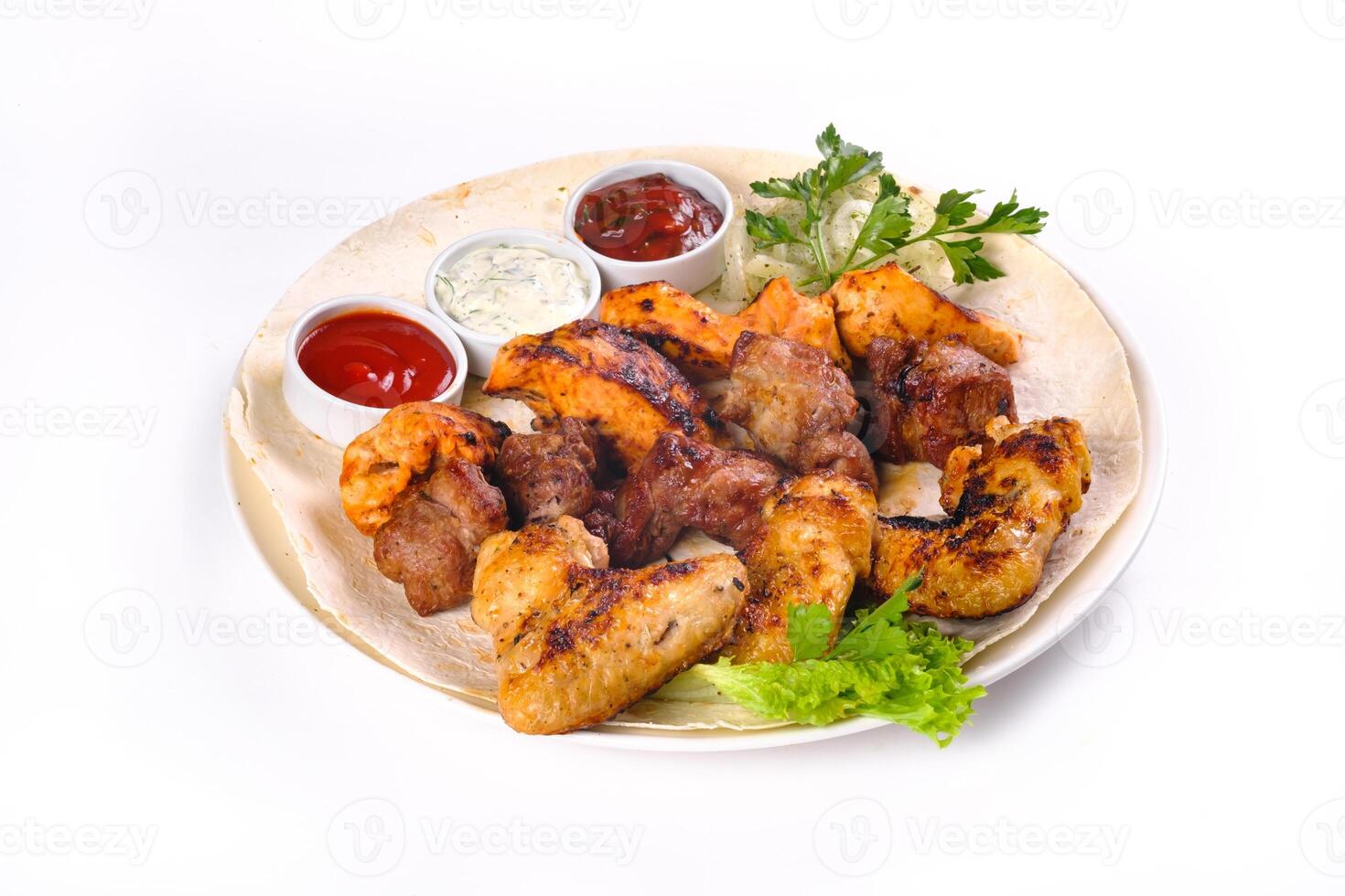 assorted meat on pita bread with vegetables and sauces on a white plate on a white isolated background photo