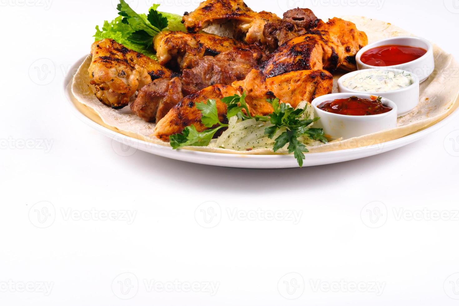 assorted meat on pita bread with vegetables and sauces on a white plate on a white isolated background photo