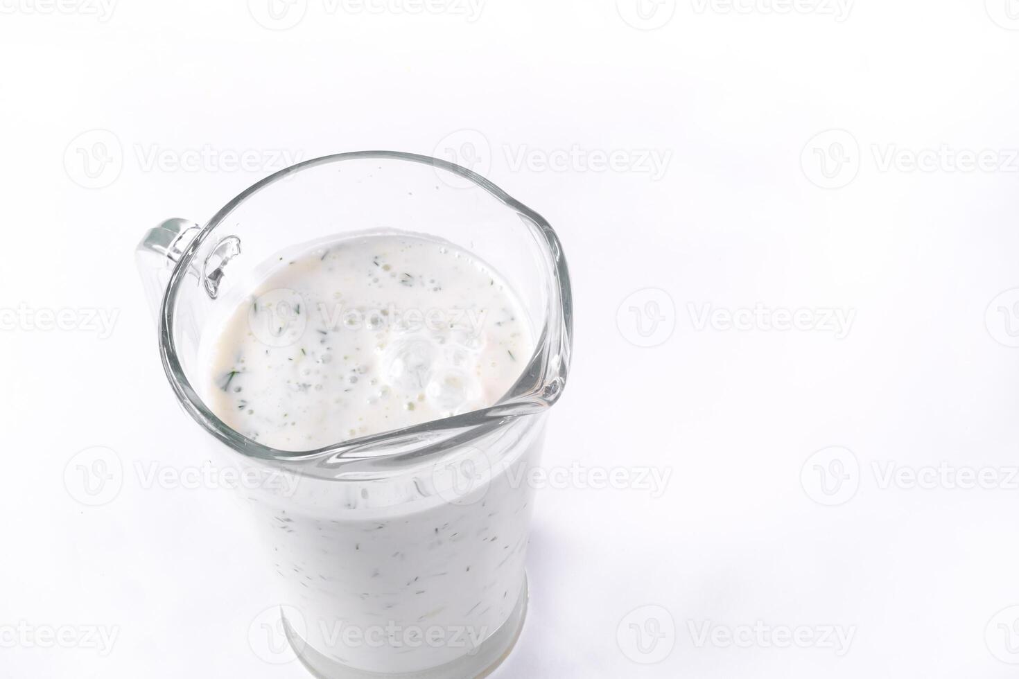A glass of ayran with dill and parsley, highlighted on a white isolated background. Cold yogurt drink photo
