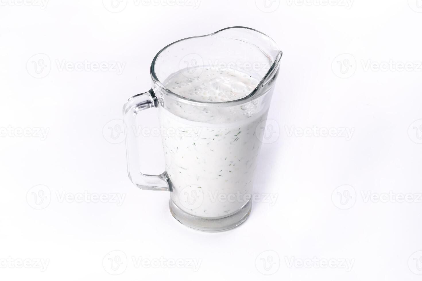 A glass of ayran with dill and parsley, highlighted on a white isolated background. Cold yogurt drink photo
