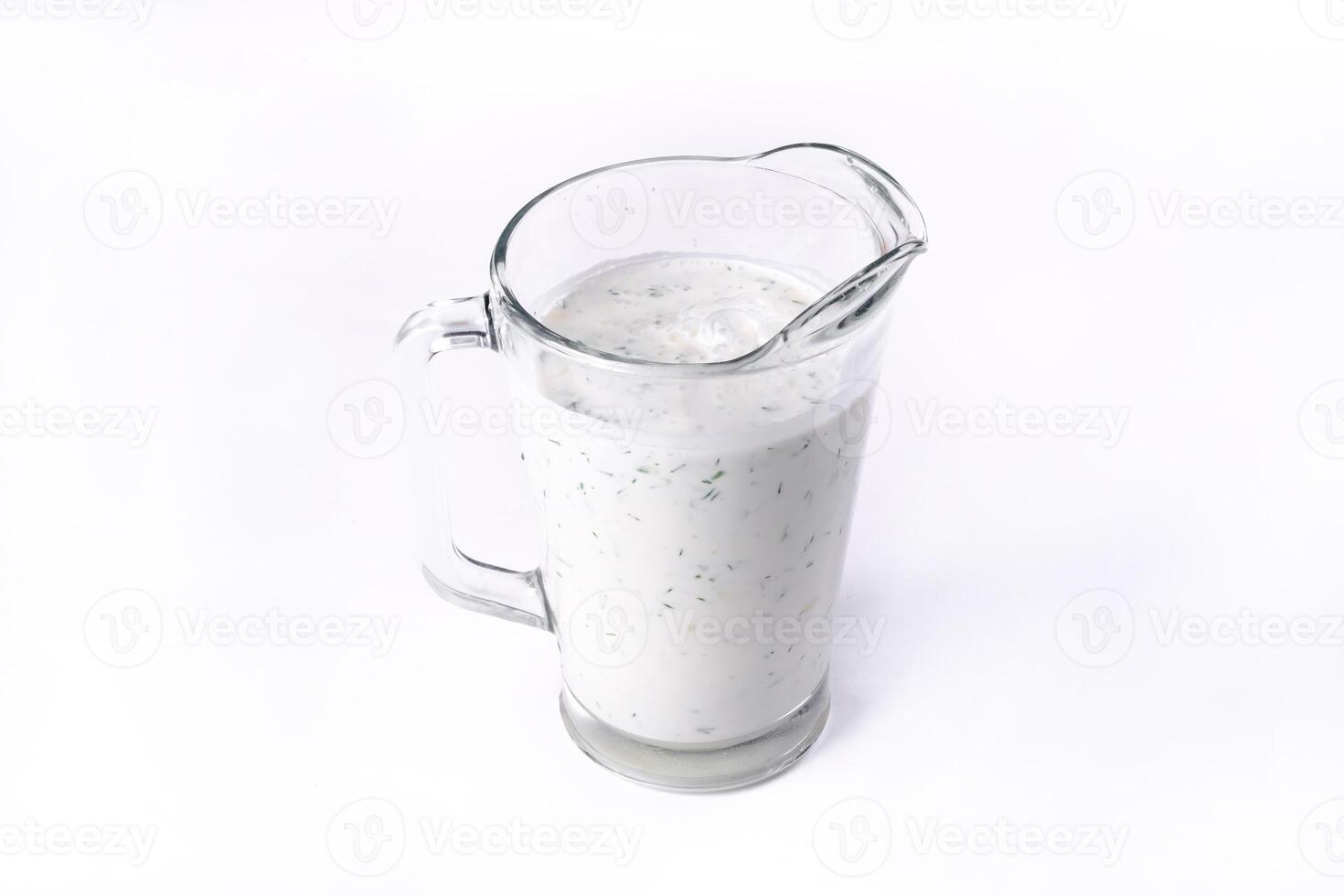 A glass of ayran with dill and parsley, highlighted on a white isolated background. Cold yogurt drink photo