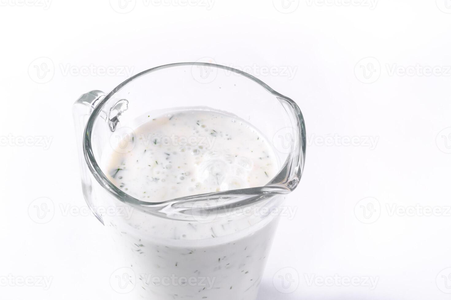 A glass of ayran with dill and parsley, highlighted on a white isolated background. Cold yogurt drink photo