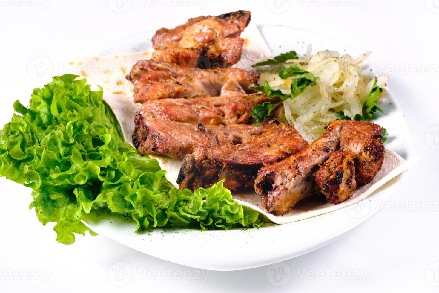 Meat kebab on ribs on lavash with onions and cabbage on a white plate, on an isolated white background photo