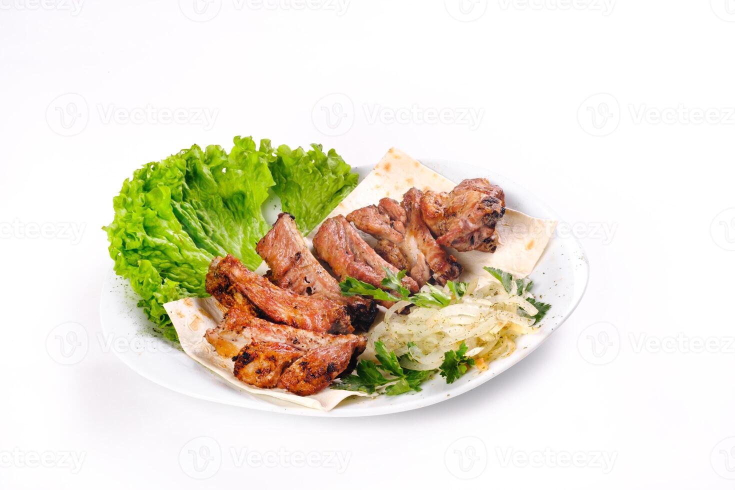 Meat kebab on ribs on lavash with onions and cabbage on a white plate, on an isolated white background photo