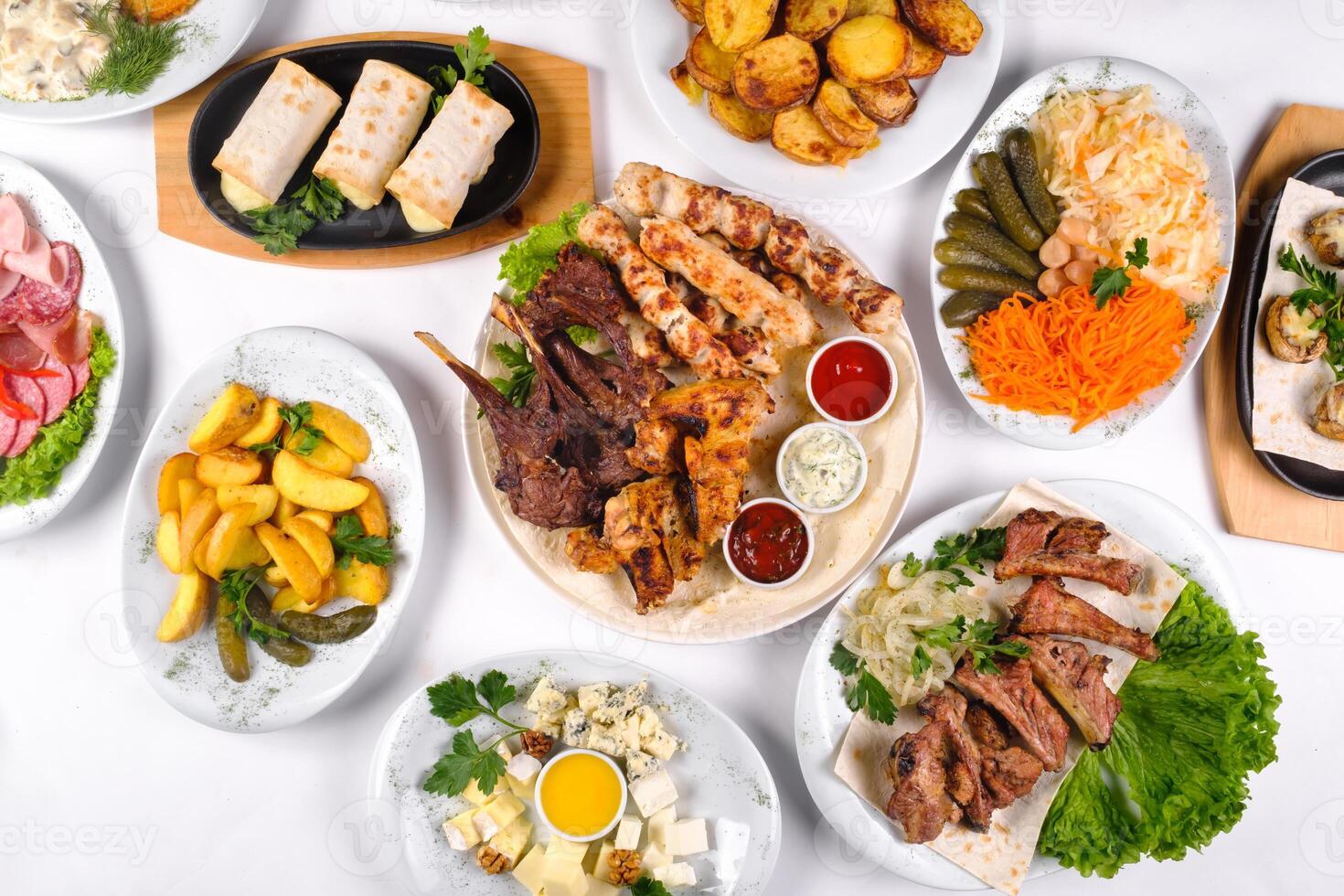 A covered table with many different dinner dishes. Lots of food on a white isolated background photo