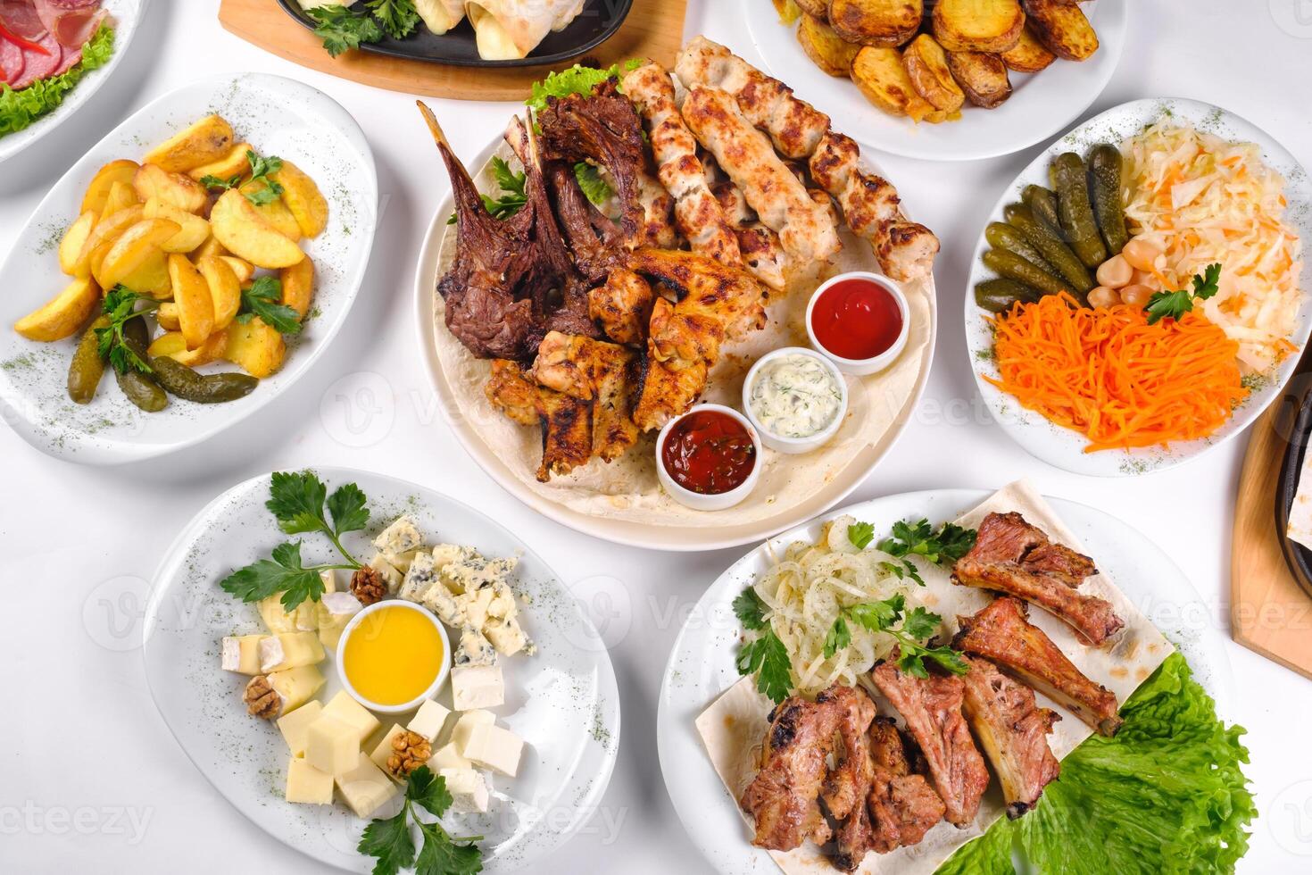 A covered table with many different dinner dishes. Lots of food on a white isolated background photo