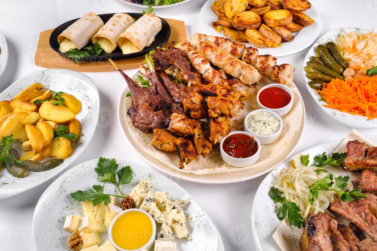 A covered table with many different dinner dishes. Lots of food on a white isolated background photo