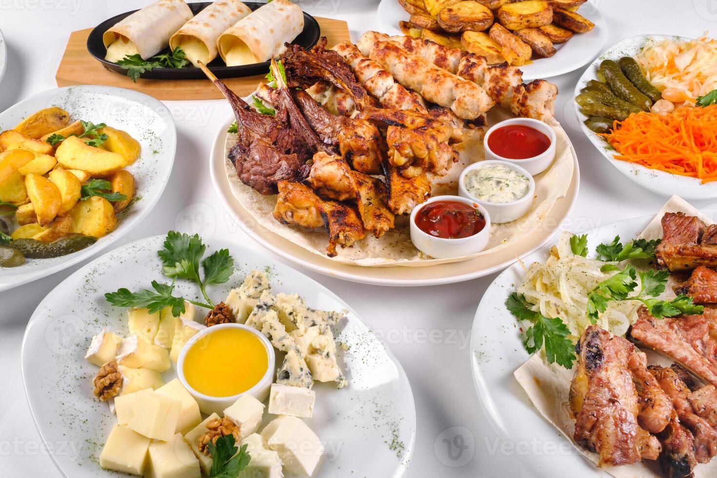 A covered table with many different dinner dishes. Lots of food on a white isolated background photo