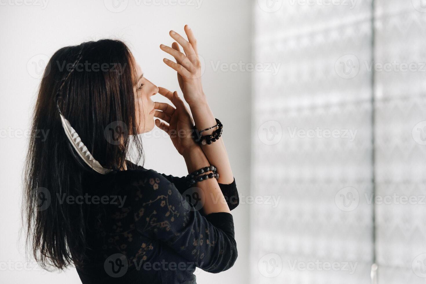 A girl in a black dress moves in a dance on a gray background. Dynamic dance photo