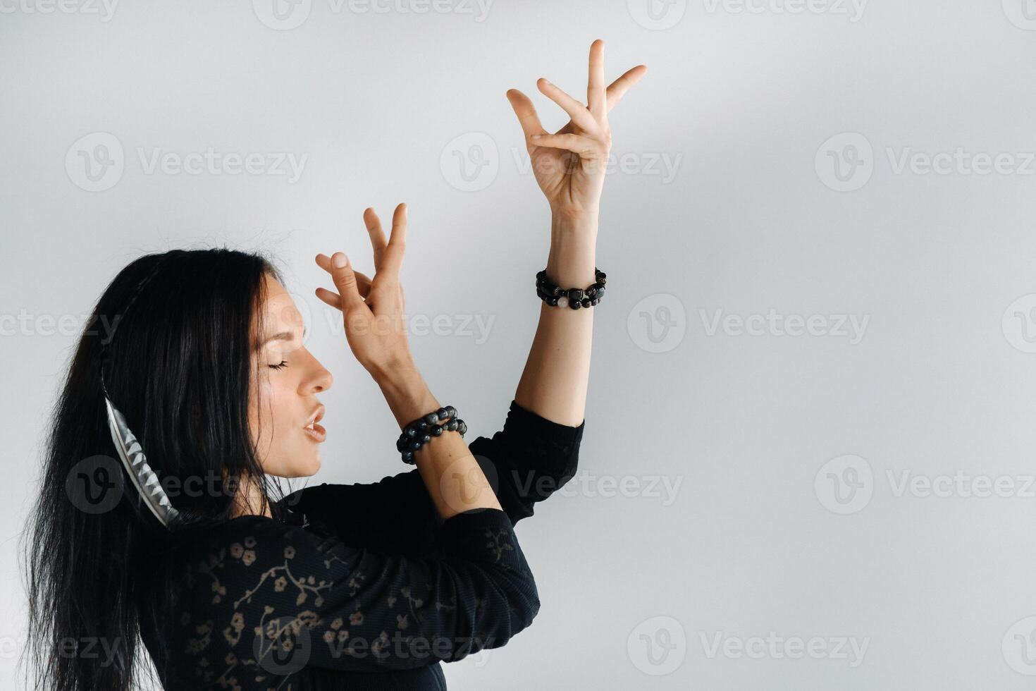 A girl in a black dress moves in a dance on a gray background. Dynamic dance photo