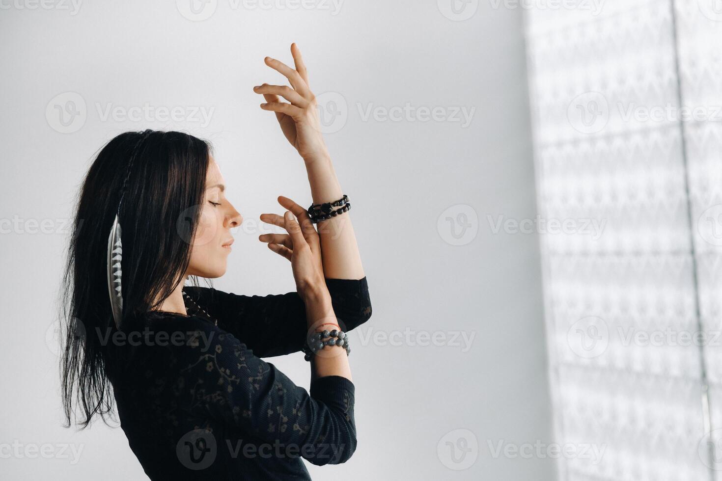 A girl in a black dress moves in a dance on a gray background. Dynamic dance photo