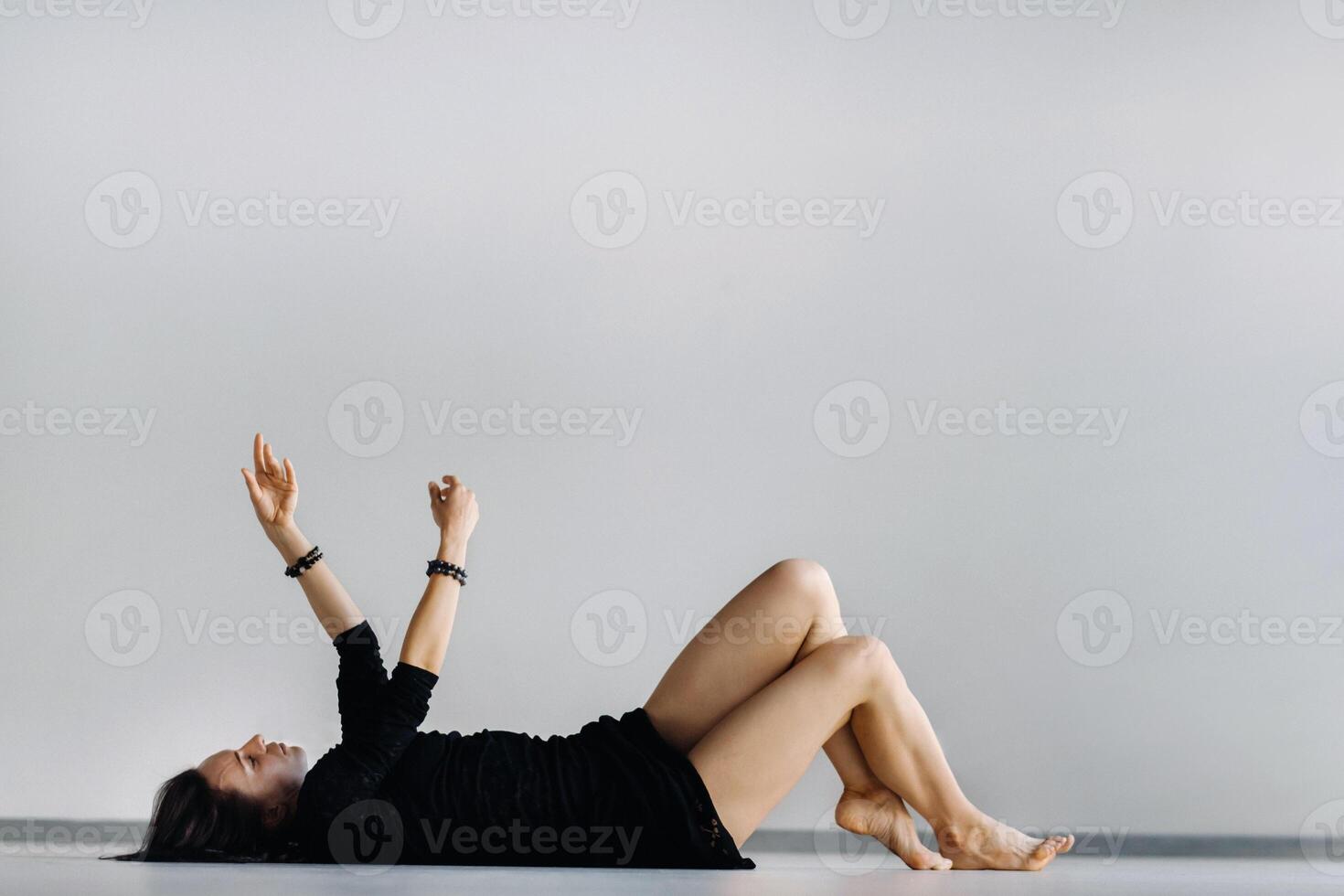 A girl in a black dress lying down moves in a dance on the floor. Dynamic dance photo