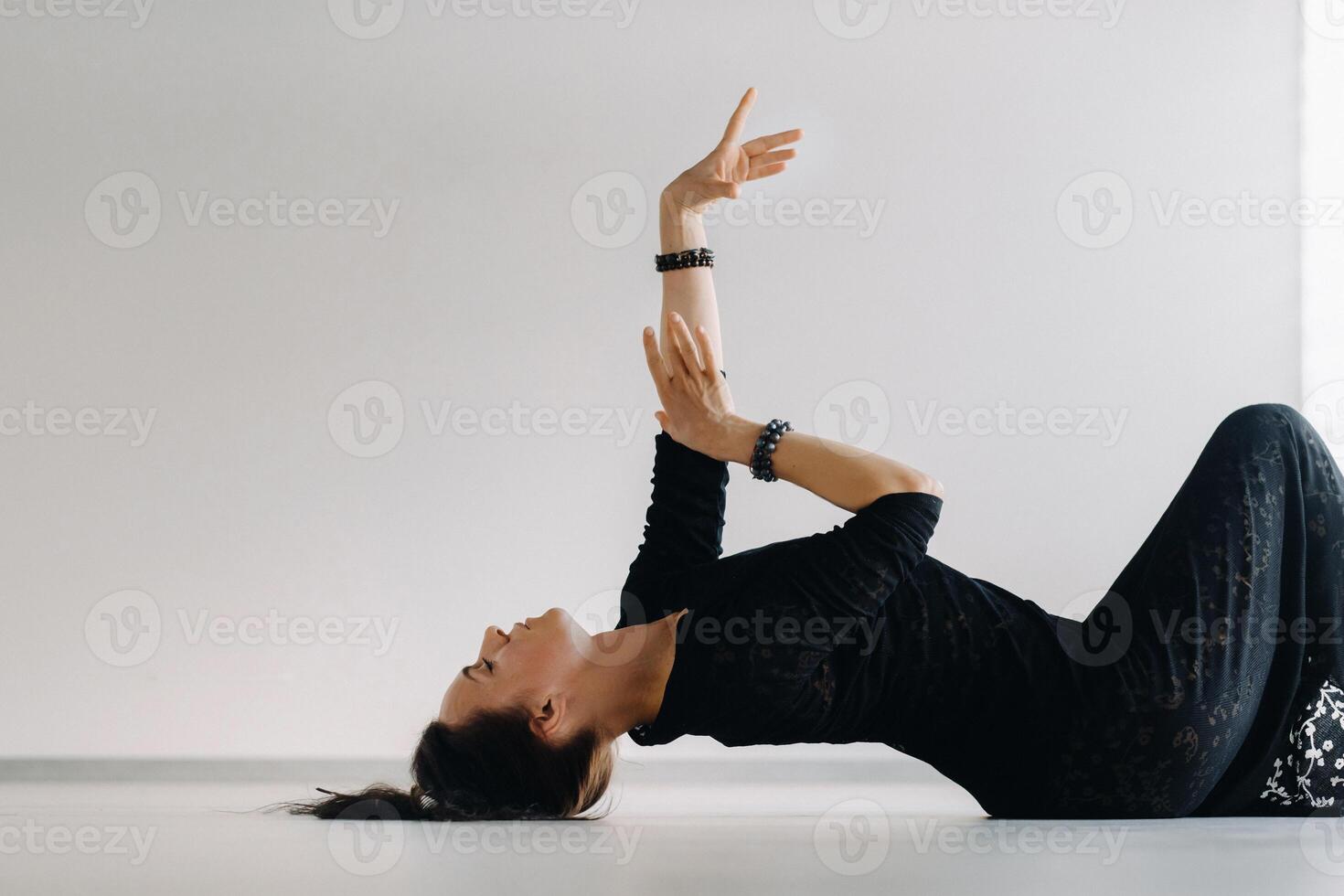 A girl in a black dress lying down moves in a dance on the floor. Dynamic dance photo