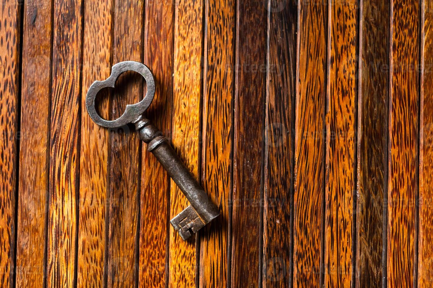 the old key lies on an old wooden table, natural textures, the concept of discoveries, secrets, answers photo