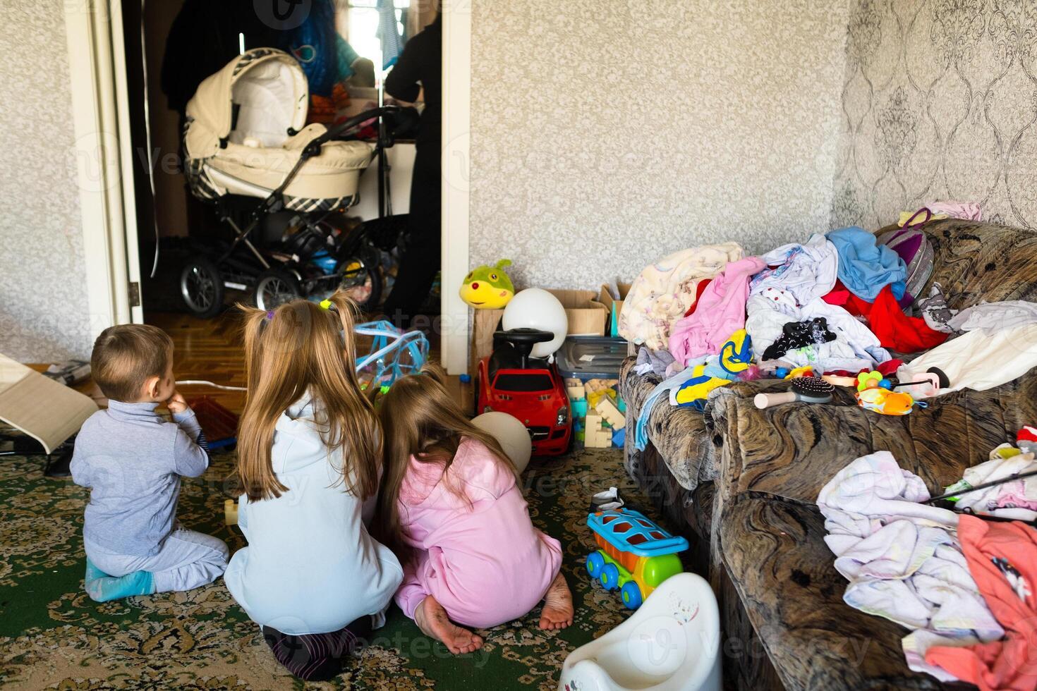 Three unrecognizable children are playing in a dirty cluttered room photo