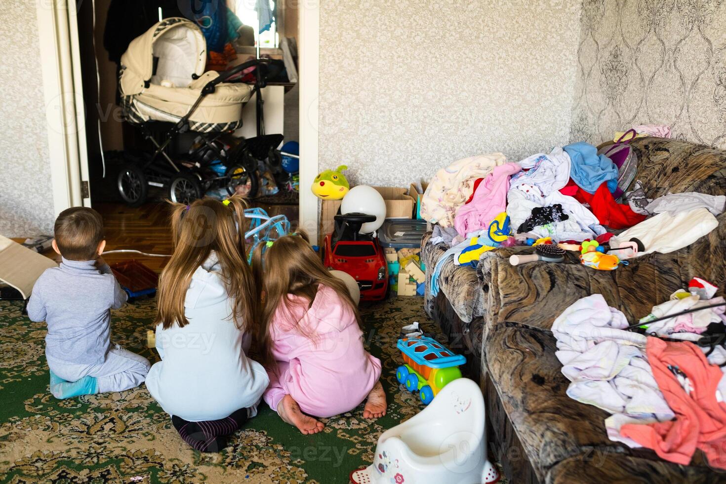 Three unrecognizable children are playing in a dirty cluttered room photo