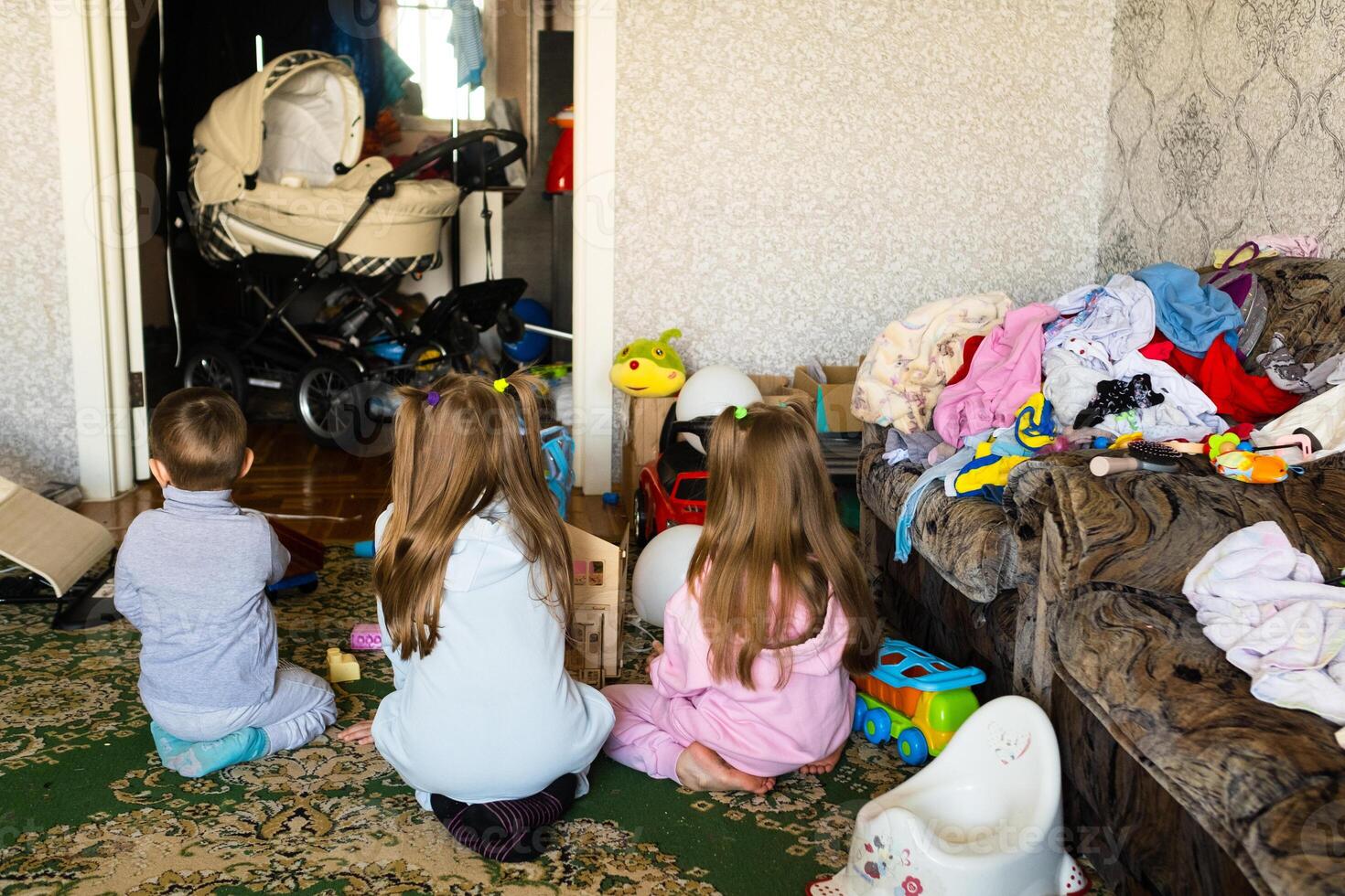 Three unrecognizable children are playing in a dirty cluttered room photo