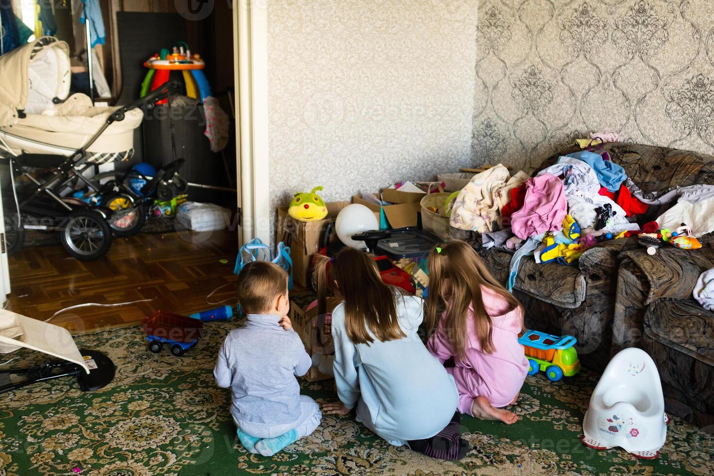Three unrecognizable children are playing in a dirty cluttered room photo