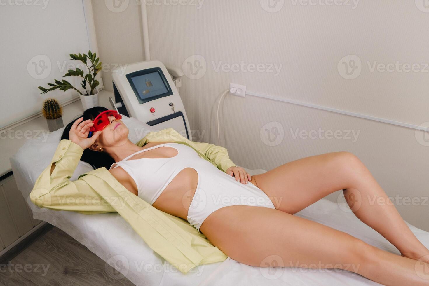 a slender woman is lying on a bed in a beauty salon before laser hair removal. look at the delicate skin on your feet and want to make it more hairless photo