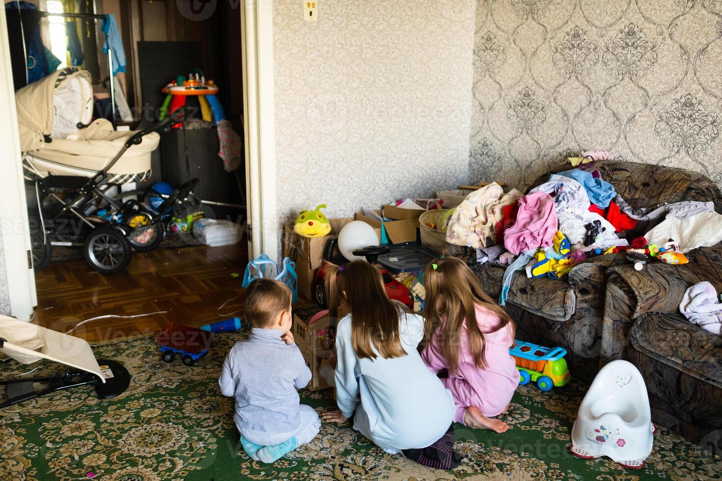 Three unrecognizable children are playing in a dirty cluttered room photo