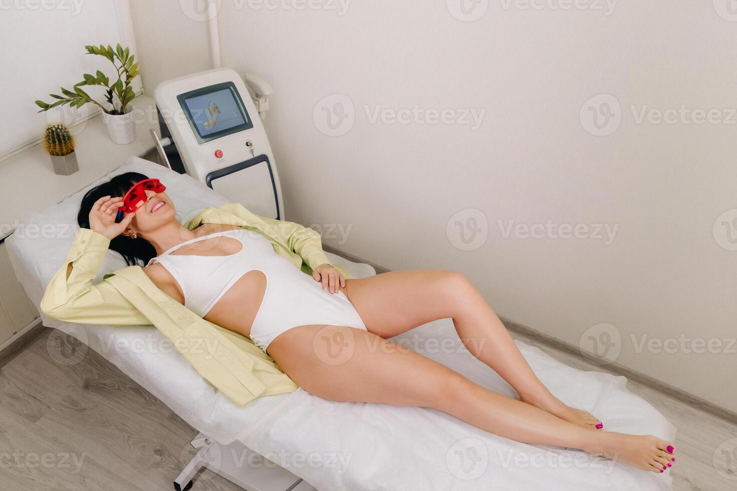 a slender woman is lying on a bed in a beauty salon before laser hair removal. look at the delicate skin on your feet and want to make it more hairless photo