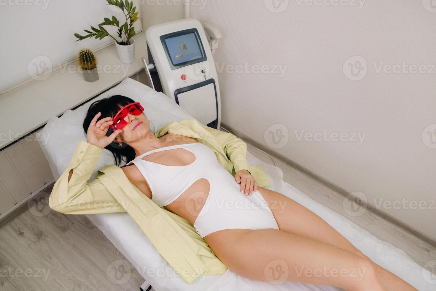 a slender woman is lying on a bed in a beauty salon before laser hair removal. look at the delicate skin on your feet and want to make it more hairless photo