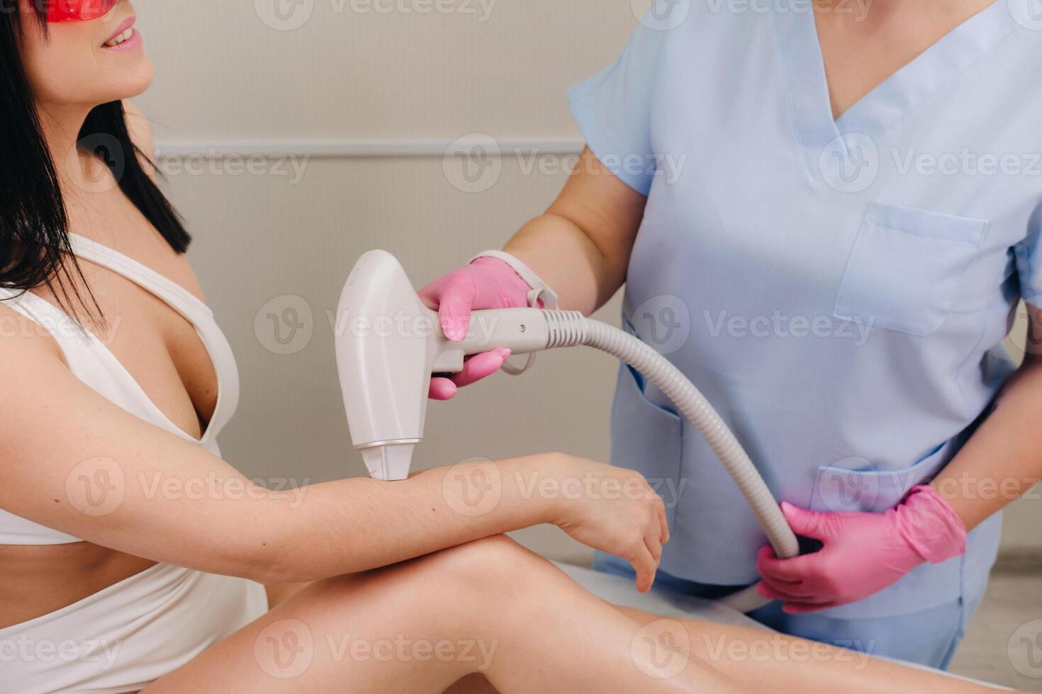A cosmetologist performs a laser hair removal procedure in the office photo