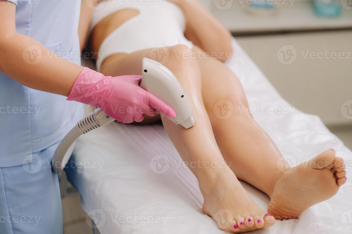 A cosmetologist performs a laser hair removal procedure in the office photo
