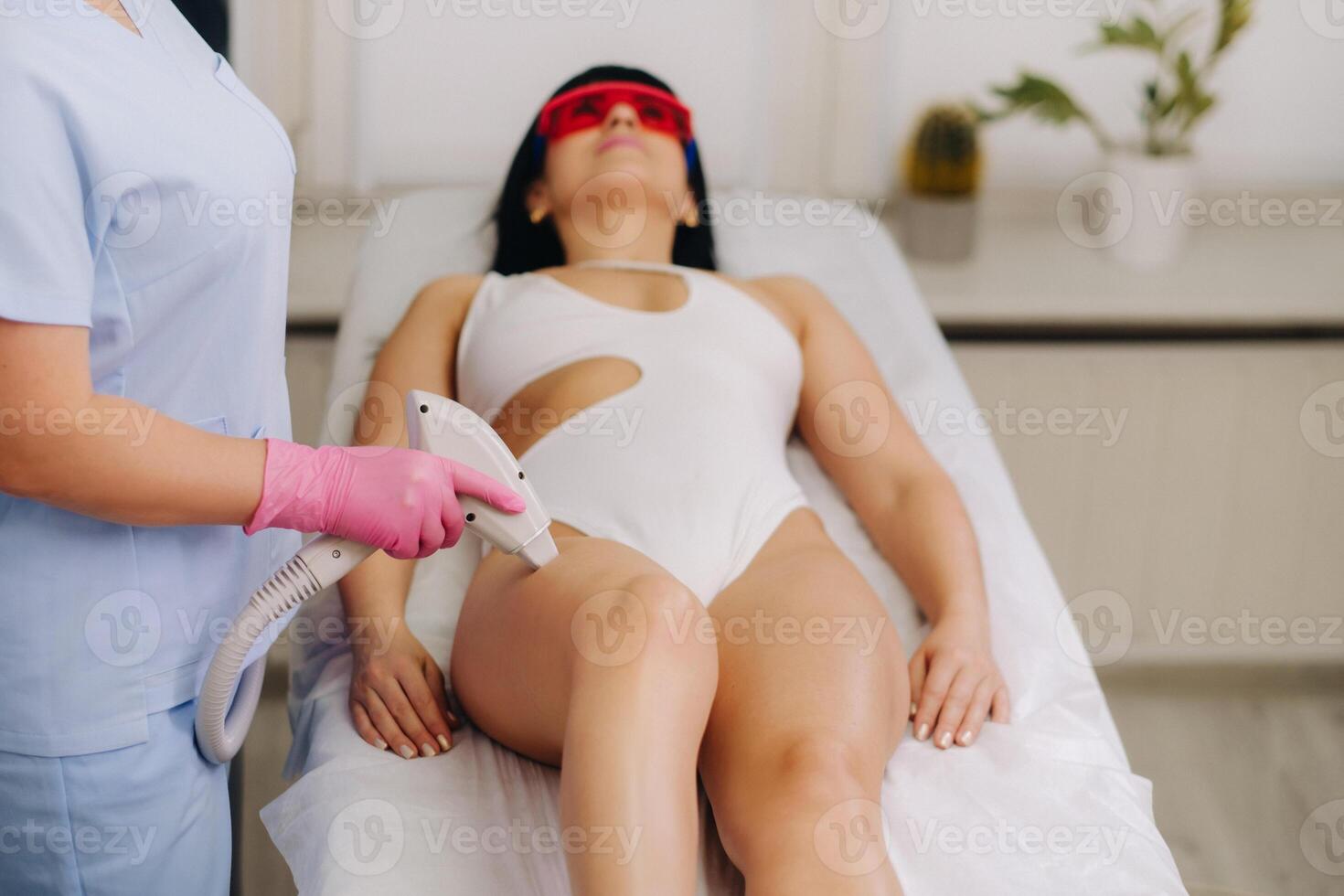 A cosmetologist performs a laser hair removal procedure in the office photo
